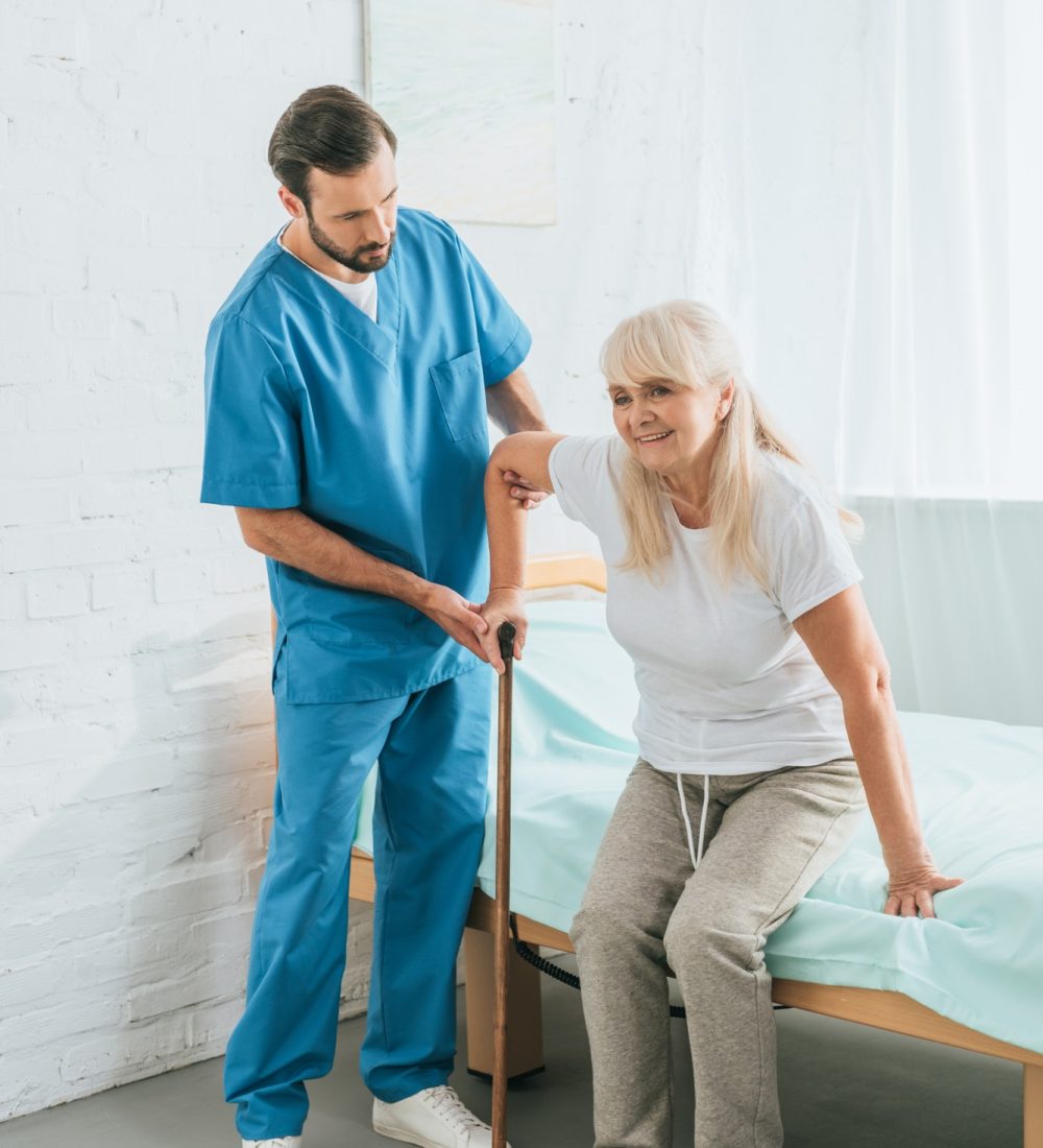 male-nurse-helping-senior-woman-with-walking-stick.jpg